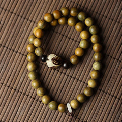 Green Sandalwood Lotus Bracelet – flat lay on bamboo mat, oval loop with lotus guru bead