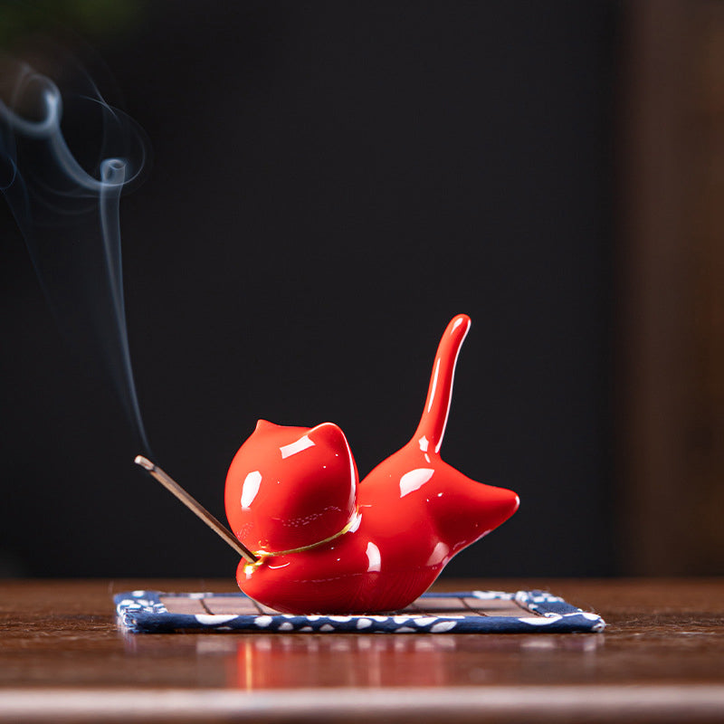 Red ceramic cat incense holder with gold collar, burning incense smoke, zen decor