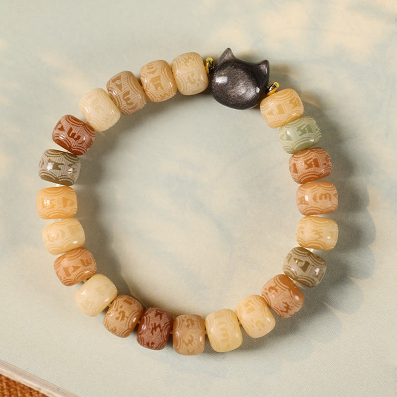 Bodhi Seed Cat Head Bracelet – Overhead view of warm-toned carved beads with obsidian cat head centerpiece, Om Mani Padme Hum prayer bead bracelet