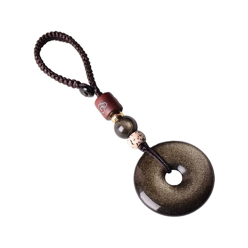 Gold Obsidian Pendant – Gold sheen obsidian keychain isolated on white background with black cord, crystal charm