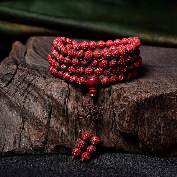 108 Mala Beads Cinnabar Bracelet – Coiled on weathered wood, red prayer bead tassel