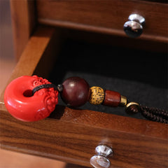 Cinnabar Peace Buckle Keychain – Side view on wooden drawer edge with dark wood bead detail