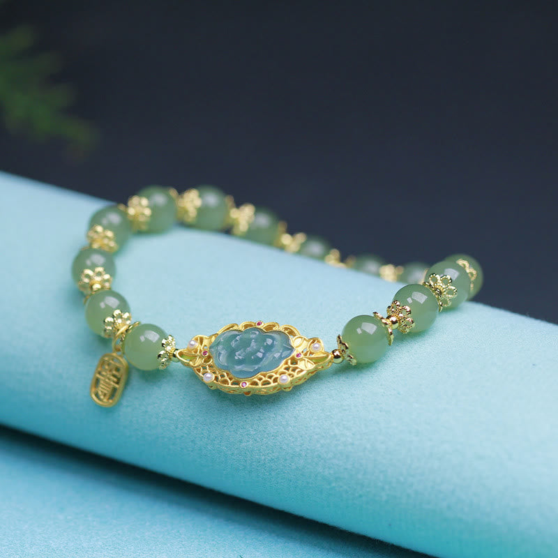 Hetian Jade Lotus Bracelet - gold filigree lotus setting with pale jade beads on turquoise fabric, beaded jade bracelet