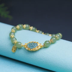 Hetian Jade Lotus Bracelet - gold filigree lotus setting with pale jade beads on turquoise fabric, beaded jade bracelet