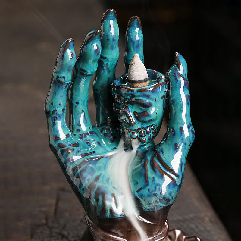 Ceramic Ghost Hand Skull Incense Burner – Turquoise skeletal hand with skull, backflow smoke close-up, dark stone surface