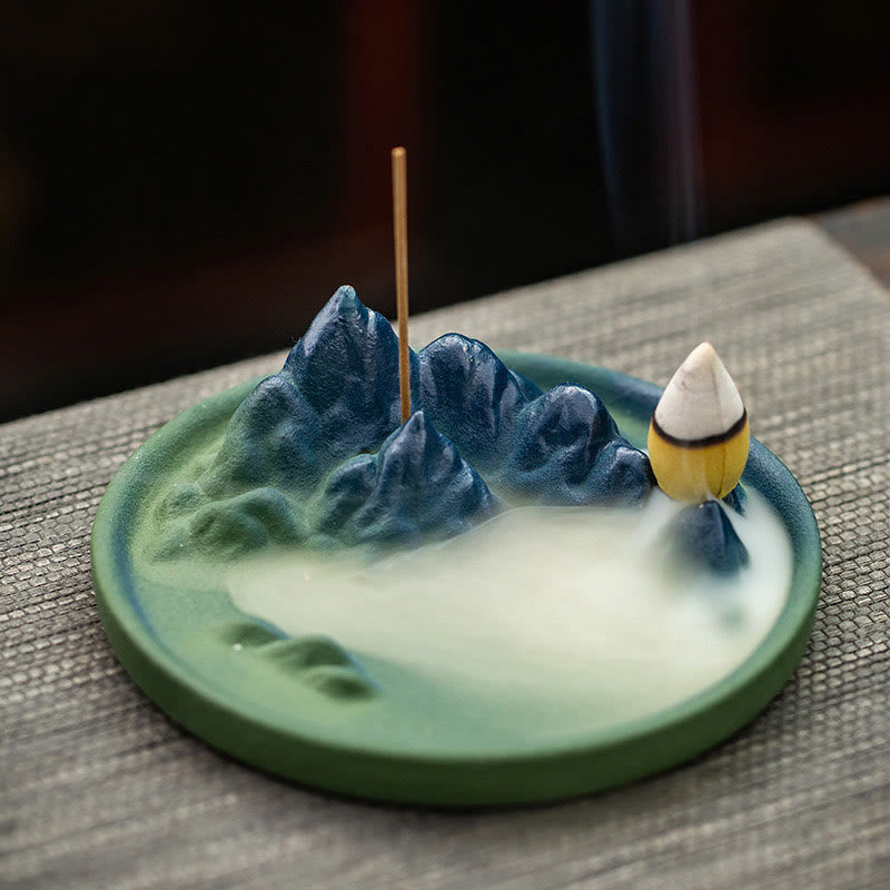 Ceramic Backflow Incense Burner – Blue mountain with gold-foil cone, smoke filling green valley on woven mat, zen