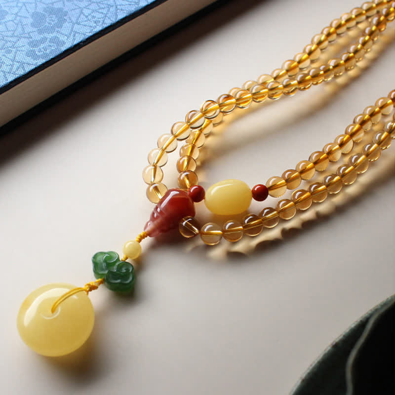 Citrine Mala Bracelet – Citrine mala beads on light surface near blue book corner detail