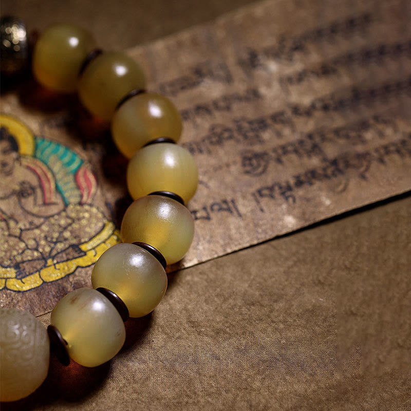 Tibetan Sheep Horn Skull Bracelet – Low angle on thangka manuscript, translucent amber bead close-up