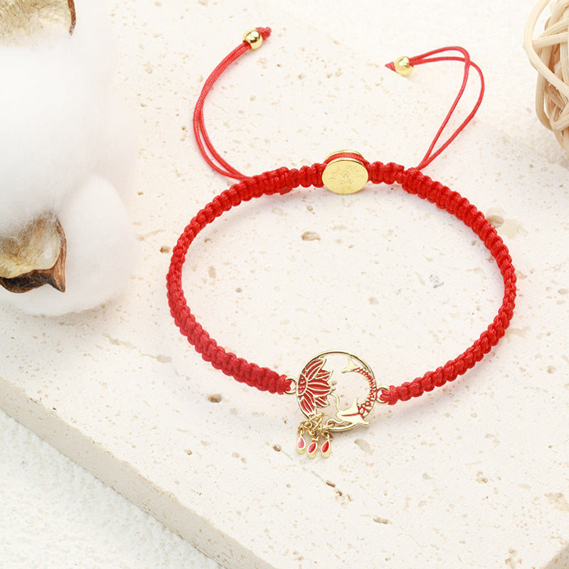 Tibetan Red String Koi Fish Bracelet – red cord on stone surface with cotton bolls, gold lotus charm, teardrop dangles