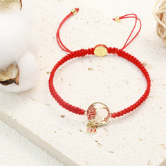 Tibetan Red String Koi Fish Bracelet – red cord on stone surface with cotton bolls, gold lotus charm, teardrop dangles
