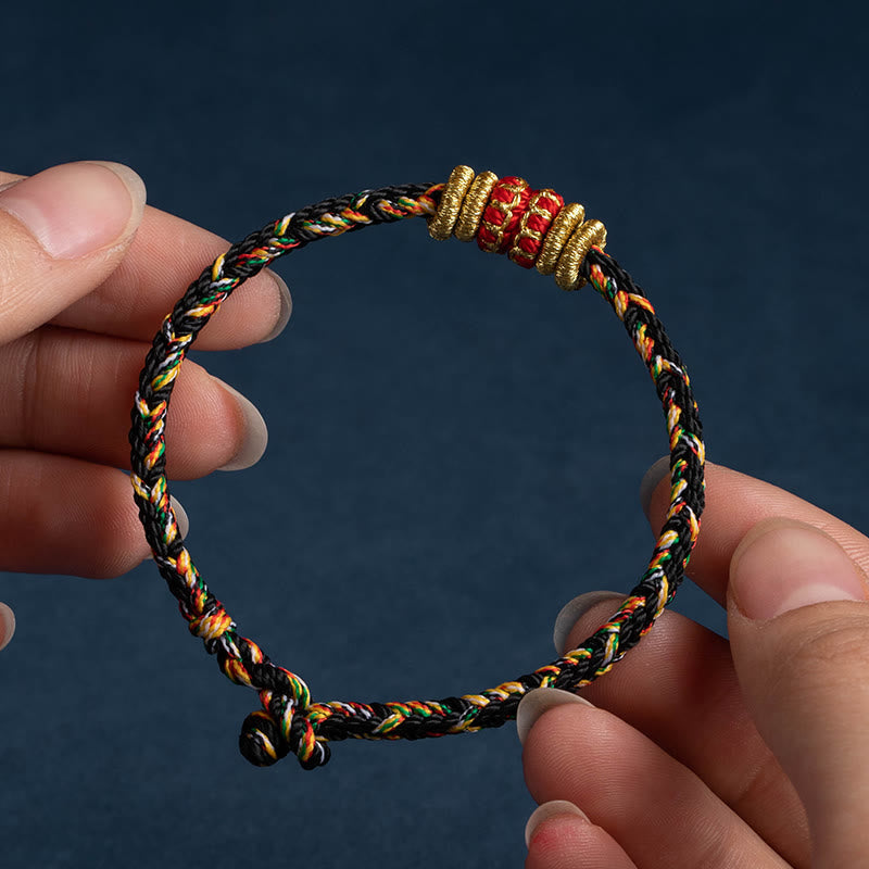 Multicolor braided rope bracelet with red gold center bead held between hands, adjustable sliding knot closure, handmade traditional Chinese lucky cord jewelry