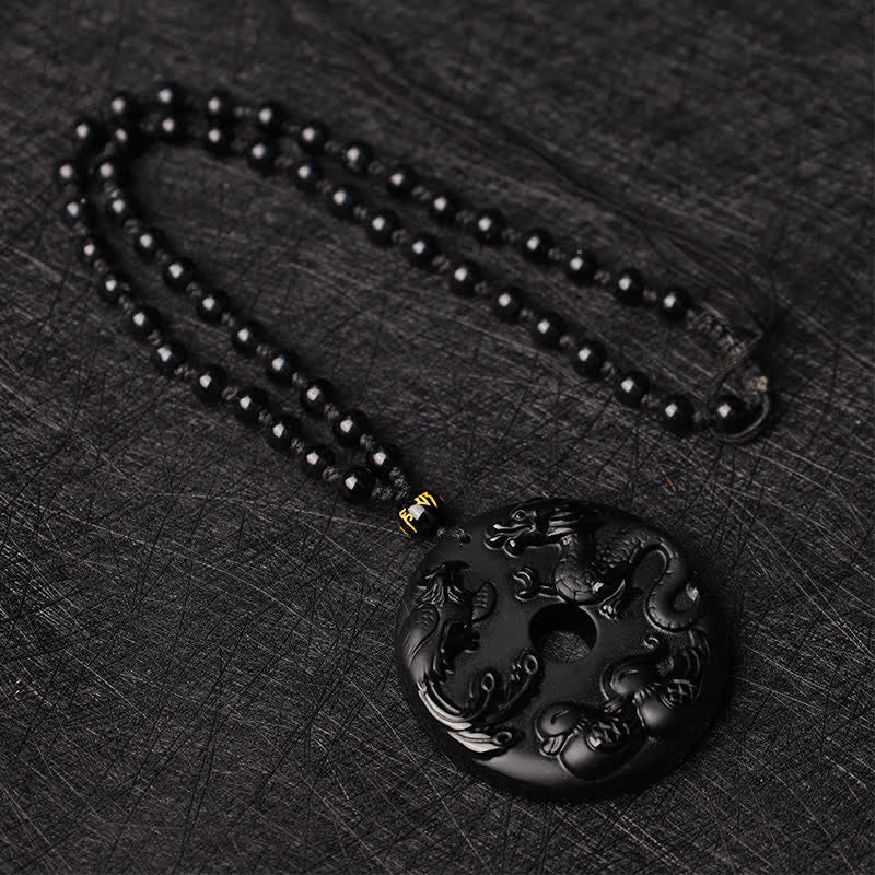 Black Obsidian Dragon Phoenix Pendant - Dragon-phoenix relief carving on polished obsidian disc on dark fabric, Protection