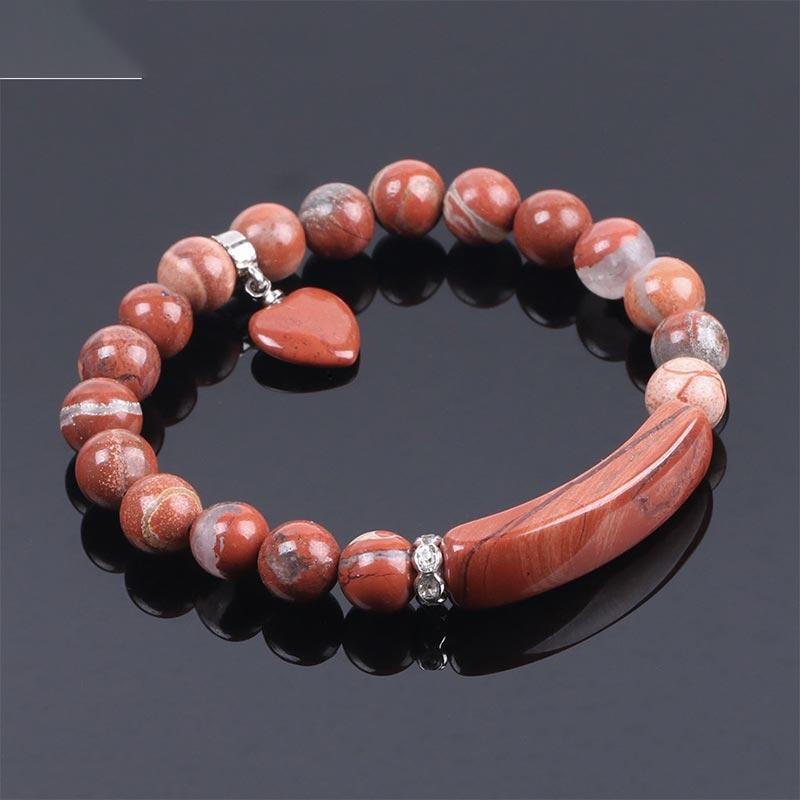 Natural Multi-Stone Love Heart Healing Bracelet - Red jasper bracelet on reflective black surface with terracotta beads, grooved bar centerpiece, and heart charm