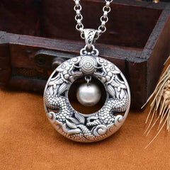 Double Dragon Copper Pendant on leather, dragon chasing pearl motif, wooden box backdrop, protective amulet