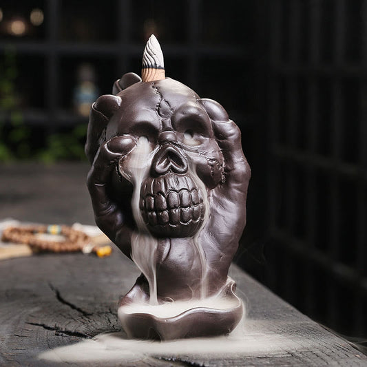 Skull Ghost Hand Incense Burner – skull cradled by skeletal hands with smoke waterfall, backflow incense
