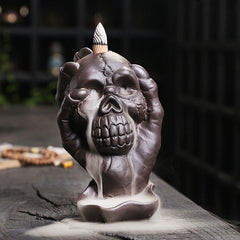 Skull Ghost Hand Incense Burner – skull cradled by skeletal hands with smoke waterfall, backflow incense