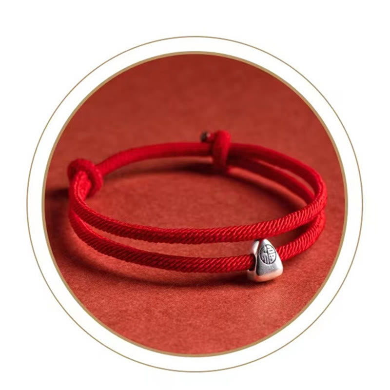 925 Silver Fu Character Braided Bracelet – Red cord bracelet with silver zongzi charm on red textured background in white-bordered circular frame, overhead flat lay