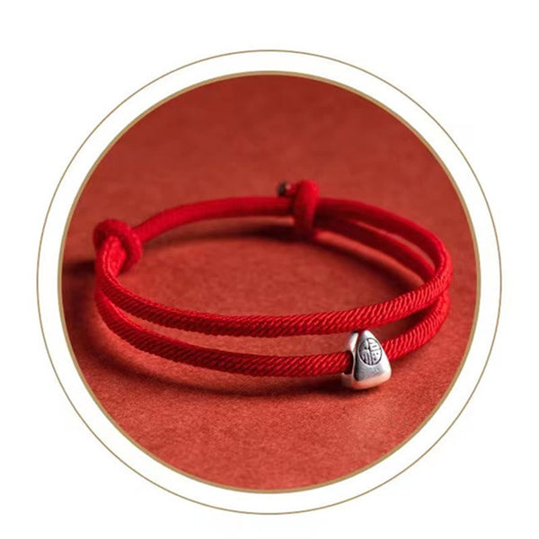 925 Silver Fu Character Braided Bracelet – Red cord bracelet with silver zongzi charm on red textured background in white-bordered circular frame, overhead flat lay