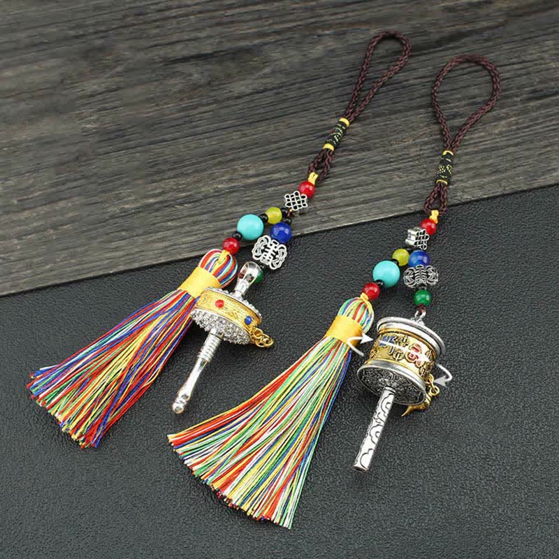 Tibetan Prayer Wheel Tassel – Two prayer wheel hanging charms with tassels on rustic wood background