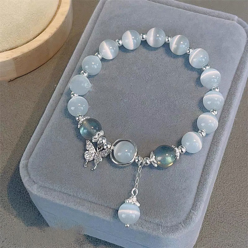 Cat's Eye Moonstone Butterfly Bracelet – Pale blue cat's eye beads with silver butterfly crystal charm and iridescent accent beads on gray velvet cushion display