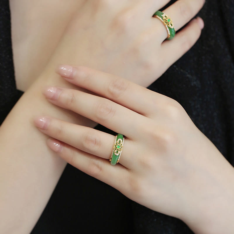 18K Gold Green Chalcedony Strength Ring – Two green jade filigree rings worn on crossed hands with natural nails, black fabric background, elevated diagonal