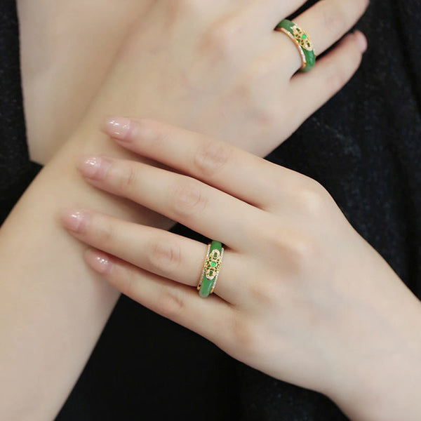 18K Gold Green Chalcedony Strength Ring – Two green jade filigree rings worn on crossed hands with natural nails, black fabric background, elevated diagonal