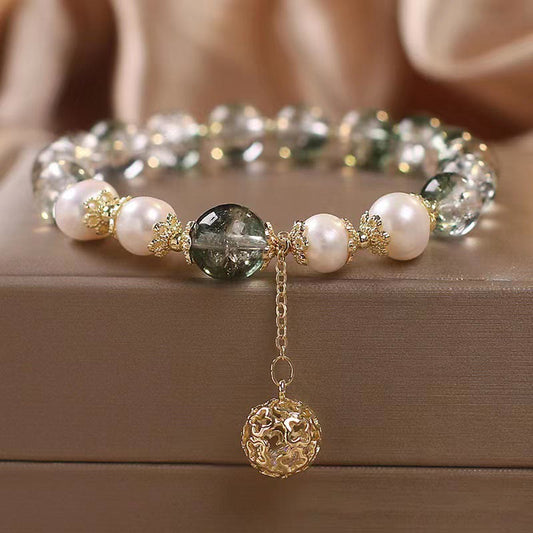Green Phantom Pearl Charm Bracelet – Green phantom quartz crystals with white pearls and gold floral spacers, filigree ball charm on chain, beige fabric low angle