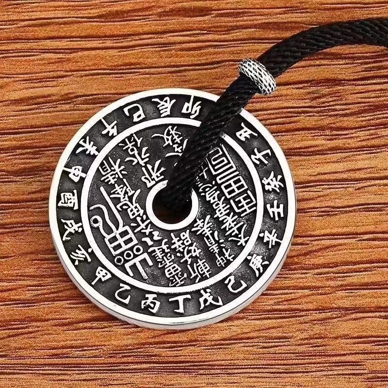 Antique Shan Gui Pendant – close-up silver Shan Gui coin with black cord on wood grain, detailed engraved talisman script, spiritual pendant