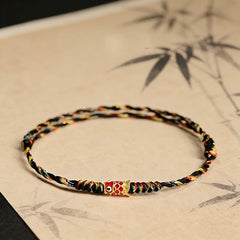 Five-Color Koi Bracelet – black multicolor woven cord with gold fish charm on bamboo art background, spiritual accessory