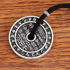 Antique Shan Gui Pendant – close-up silver Shan Gui coin with black cord on wood grain, detailed engraved talisman script, spiritual pendant