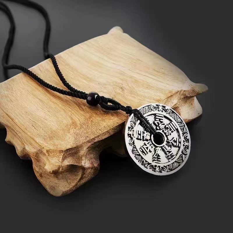 Antique Shan Gui Pendant – silver coin pendant on driftwood with black braided cord, dark gray background, antique mountain ghost charm