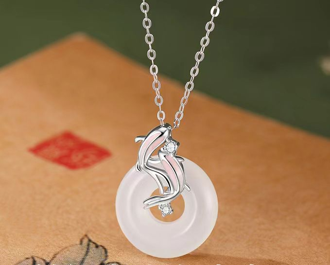 Koi Fish Peace Pendant – silver koi fish on white jade circle over beige fabric, zen harmony amulet