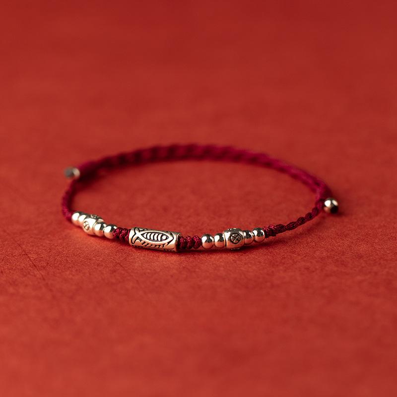 Koi Red String Bracelet – burgundy cord bracelet with silver fish bead and round beads on red surface, fortune jewelry