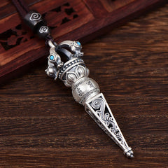 Tibetan Dorje Vajra Rotatable Pendant – Oxidized silver phurba dagger with turquoise accents and Sanskrit mantras on brown wood grain with carved lattice panel