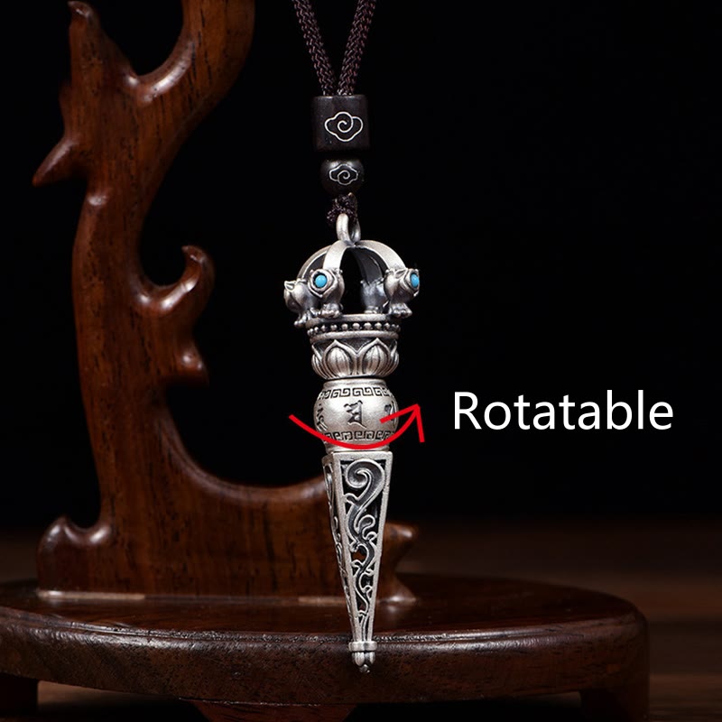 Tibetan Dorje Vajra Rotatable Pendant – Silver dorje with rotatable middle barrel, lotus base and turquoise crown on dark cord, black backdrop with carved wood stand