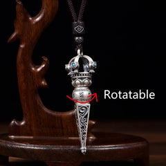 Tibetan Dorje Vajra Rotatable Pendant – Silver dorje with rotatable middle barrel, lotus base and turquoise crown on dark cord, black backdrop with carved wood stand