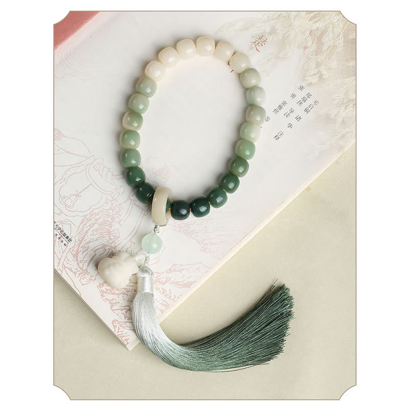 Bodhi Seed Lotus Wisdom Wrist Mala – Green to white gradient handheld prayer beads on open book, lotus carving and silk tassel