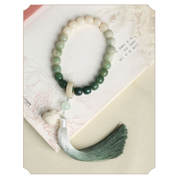 Bodhi Seed Lotus Wisdom Wrist Mala – Green to white gradient handheld prayer beads on open book, lotus carving and silk tassel
