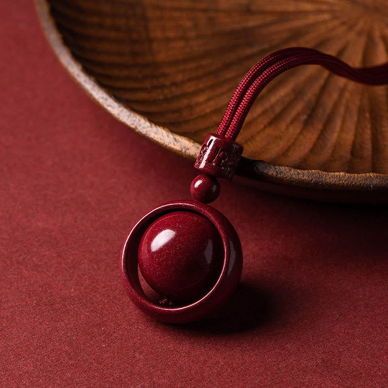 Cinnabar PiXiu Necklace – Pendant leaning against wooden bowl edge on red surface, spiritual jewelry