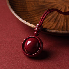 Cinnabar PiXiu Necklace – Pendant leaning against wooden bowl edge on red surface, spiritual jewelry