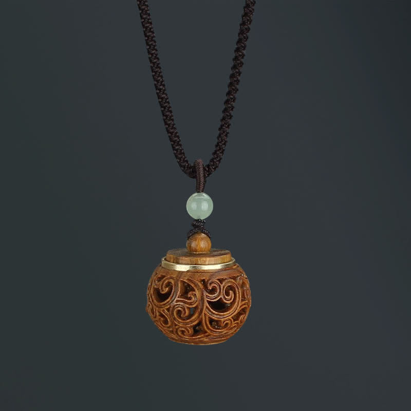 Om Mani Padme Hum Necklace – Round wooden diffuser pendant with filigree scrollwork, gold rim, jade bead, dark bg