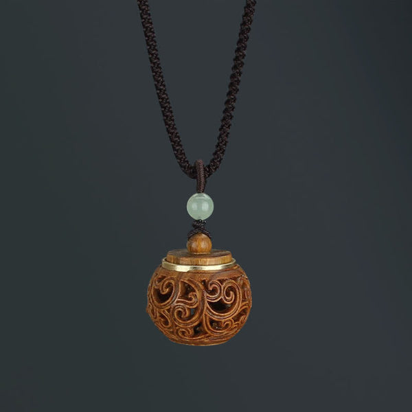 Om Mani Padme Hum Necklace – Round wooden diffuser pendant with filigree scrollwork, gold rim, jade bead, dark bg