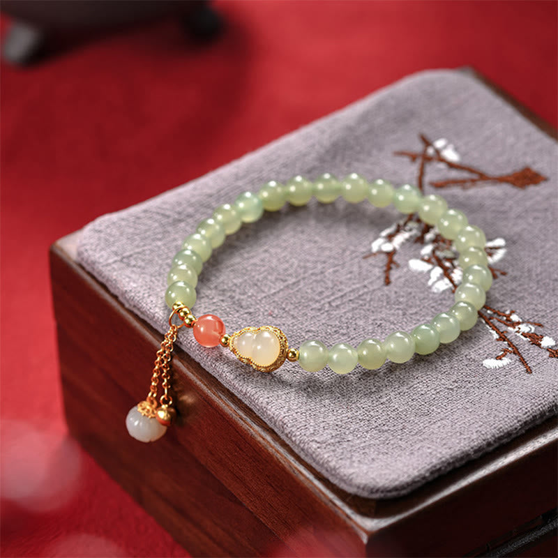 Hetian Jade Bracelet on embroidered plum blossom cushion in wooden box, red background, cultural heritage gift