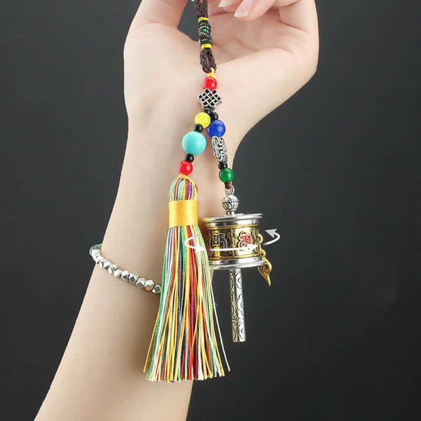 Tibetan Prayer Wheel Tassel – Hand holding spinning prayer wheel with mantras and rainbow tassel