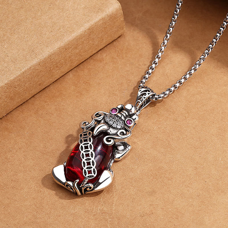 Garnet PiXiu Necklace – Ornate silver PiXiu with garnet gemstone on craft paper background, wealth necklace