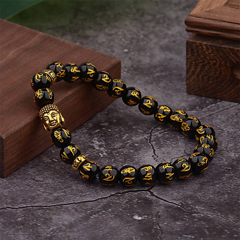Tibetan Buddha Om Mani Padme Hum Amulet Bracelet - faceted black obsidian beads with gold mantra inscriptions, silver Buddha head charm with urna and ushnisha, silver scrollwork spacer beads on dark embossed surface