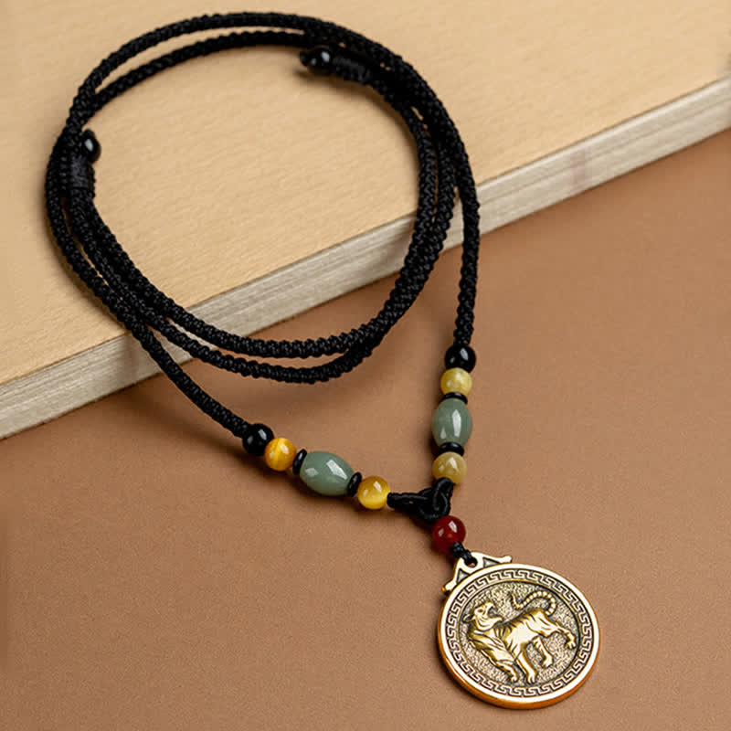 12 Chinese Zodiac Fortune Necklace Pendant – Tiger zodiac pendant flat lay, antique gold circular medallion with tiger relief and meander border, adjustable black braided cord with jade amber carnelian beads, warm brown leather background, traditional Chinese necklace