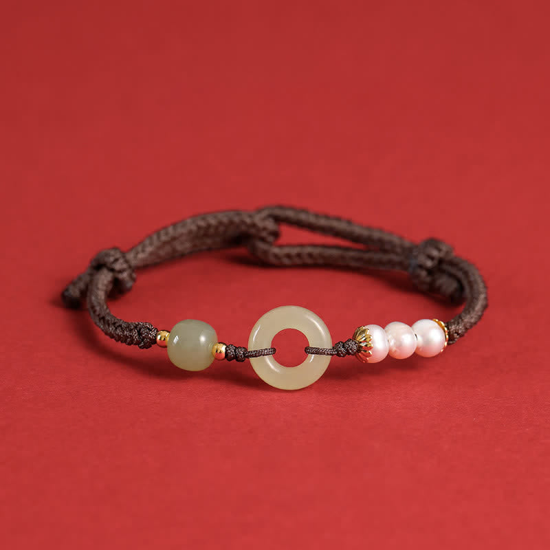 Hetian Jade Pearl Peace Buckle Bracelet – dark brown cord with celadon jade disc pearls and gold spacers, red background flat lay