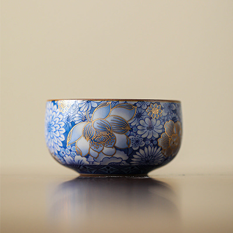 Lotus Chrysanthemum Ceramic Tea Cup - Handheld blue-white cup with gold lotus detail, ornate porcelain