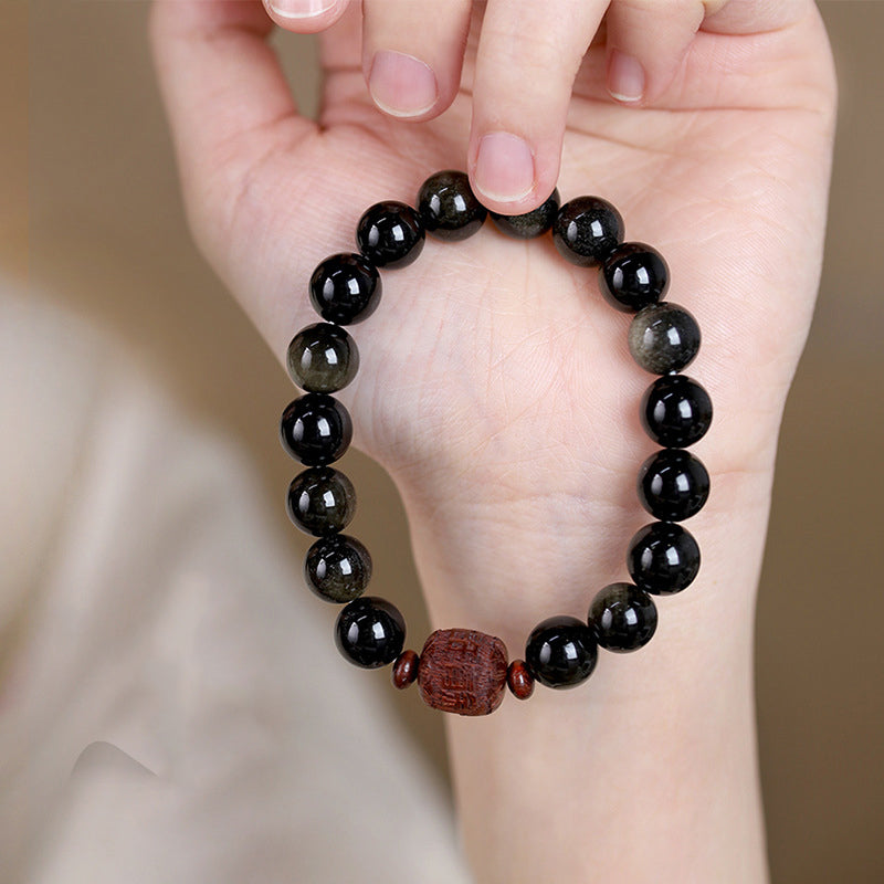 Gold Sheen & Rainbow Obsidian Fu Bracelet – held in hand showing carved center, stone bead bracelet